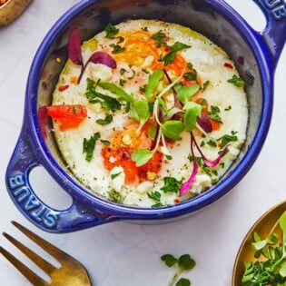 cooked baked eggs in a small baking dish next to a fork.