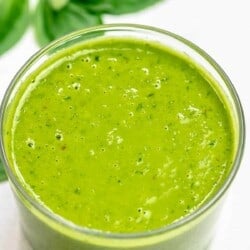 basil vinaigrette in a small jar with basil leaves in the background.