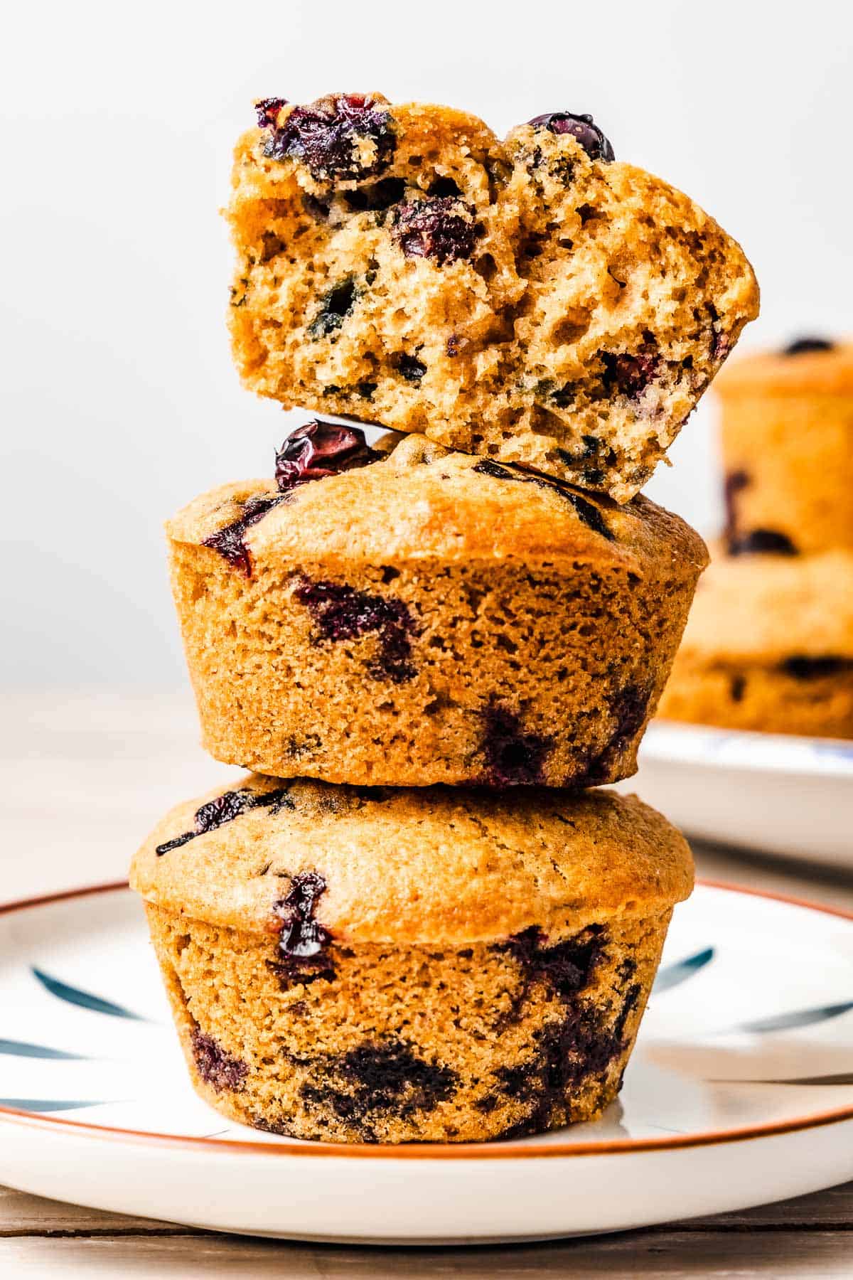 a half of a blueberry muffing stacked on top of two a whole blueberry muffin on a plate.