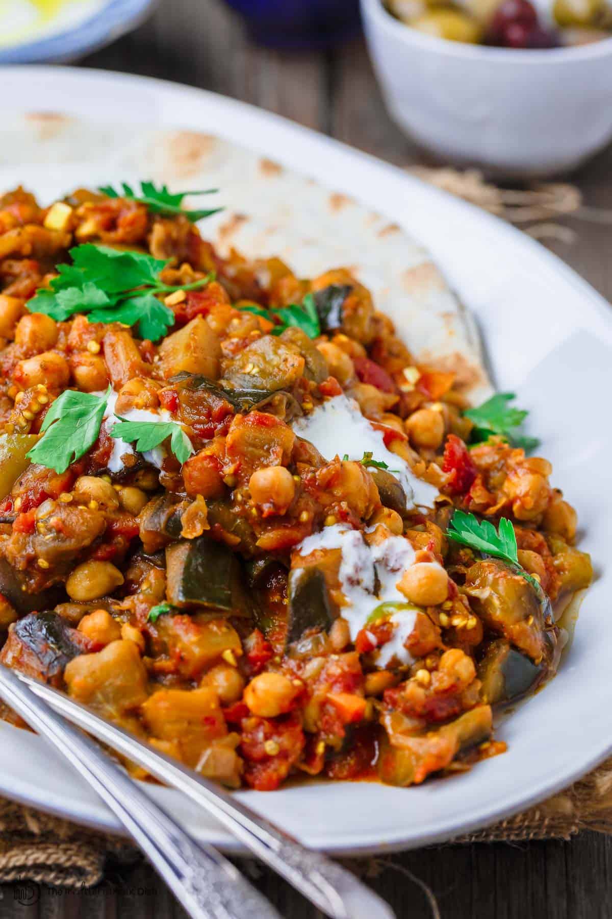 Eggplant stew served with side of pita a bowl of olives to the side