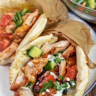 chicken doner kebab wrapped in a pita with tomato and cucumber salad and drizzled with sauce.