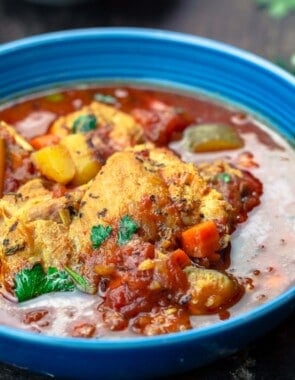 a serving of chicken stew garnished with parsley in a blue bowl.