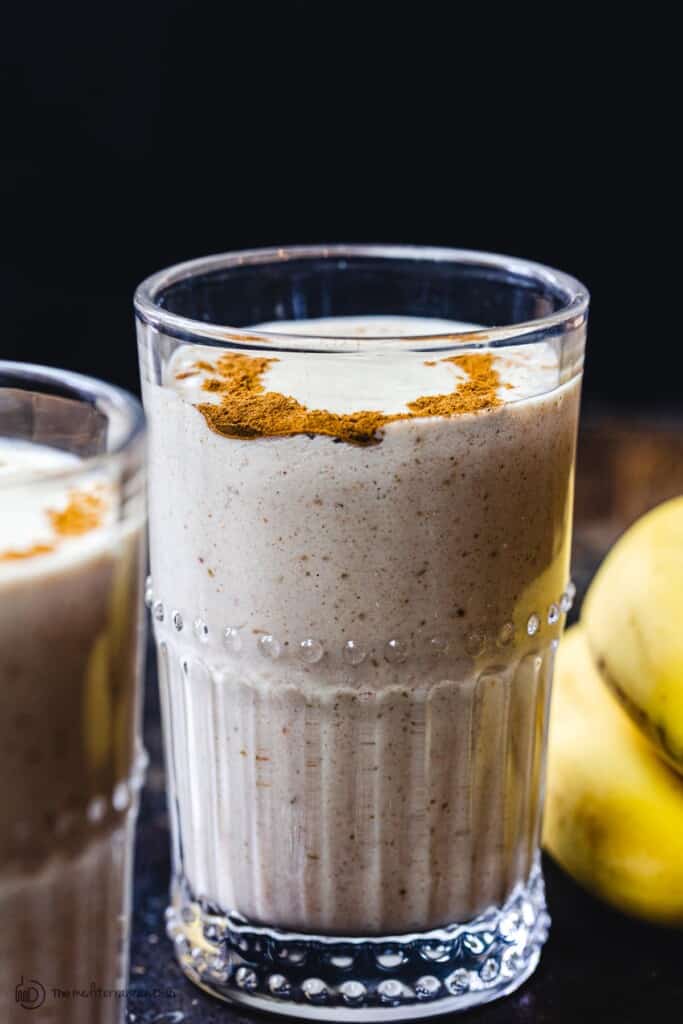 Tahini Date Banana Shake in glass. Bananas on the side