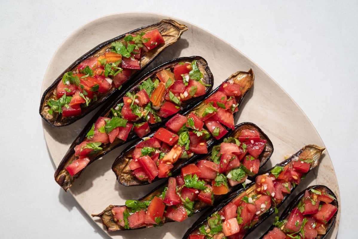 An overhead close up photo of 6 pieces of eggplant bruschetta on a platter.