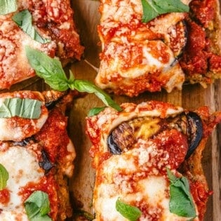 four eggplant parmesan sandwich slices on a serving board.