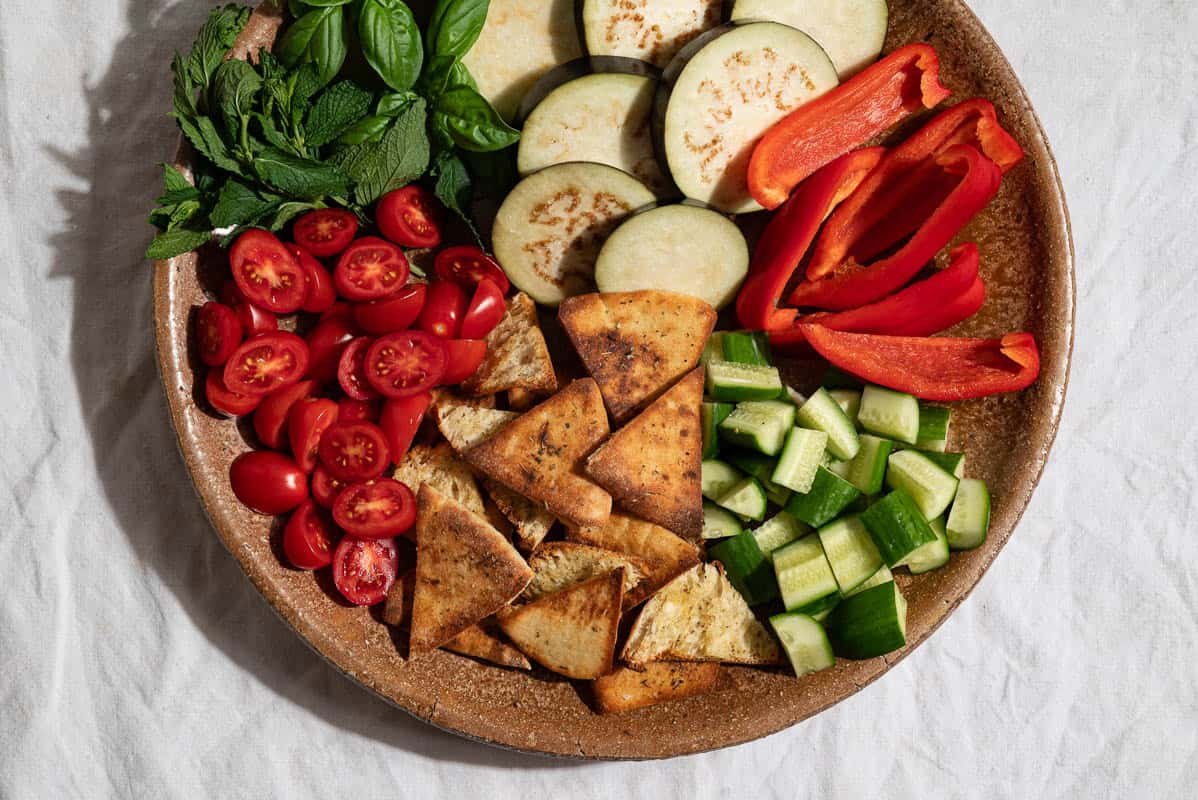 An overhead photo of the uncooked ingredients for the grilled eggplant salad on a platter.