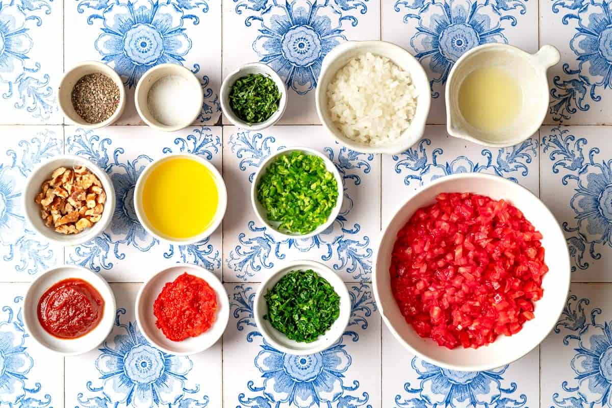 Ingredients for ezme turkish salsa including tomatoes, yellow onion, turkish red pepper paste, tomato paste, hot green peppers, parsley, mint, olive oil, lemon, salt, black pepper and walnuts.