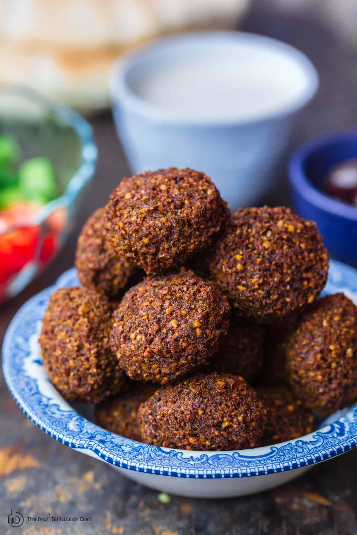 Falafel served in bowl with a side salad, tahini and pita bread