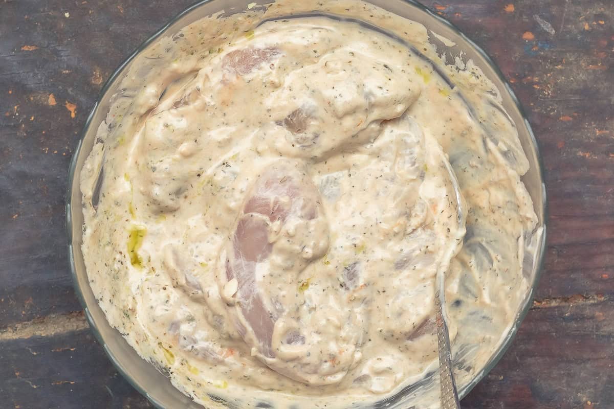 Chicken gyros marinating in bowl.