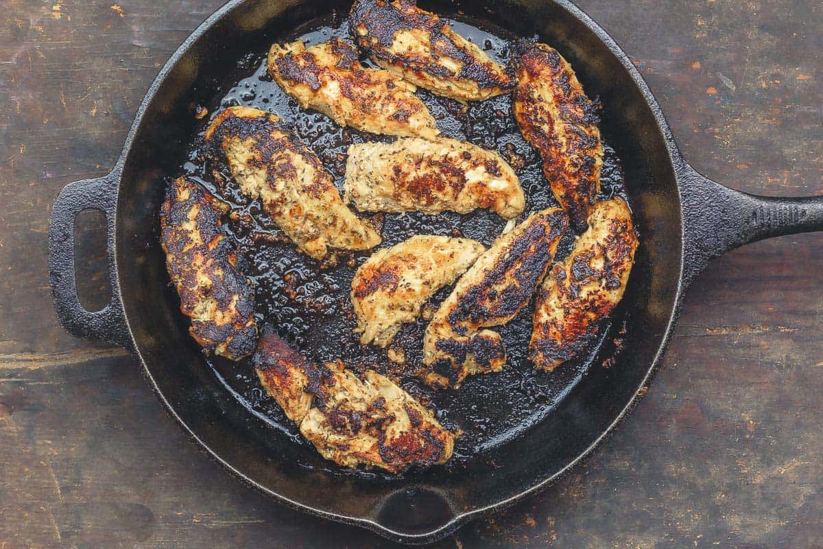 Chicken tenders cooked in a cast iron pan.