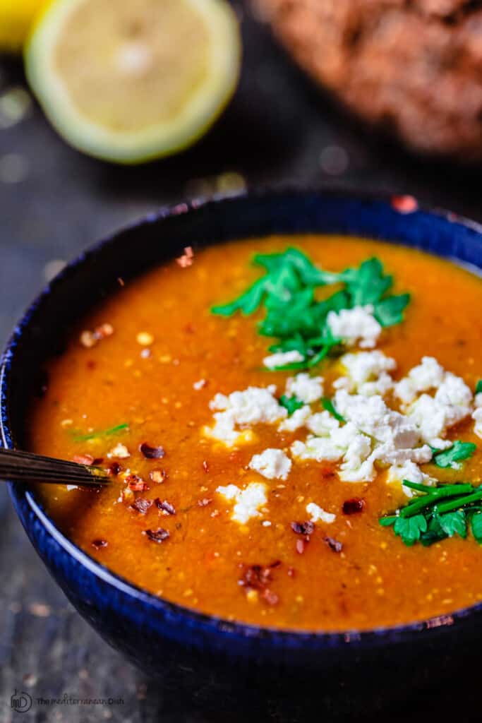 Greek red lentil soup served in a bowl with a sprinkle of feta cheese on top. Crusty bread to the side