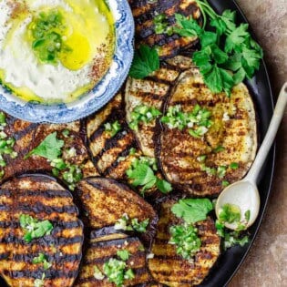 Mediterranean eggplant slices topped with infused olive oil with a serving dish of whipped feta