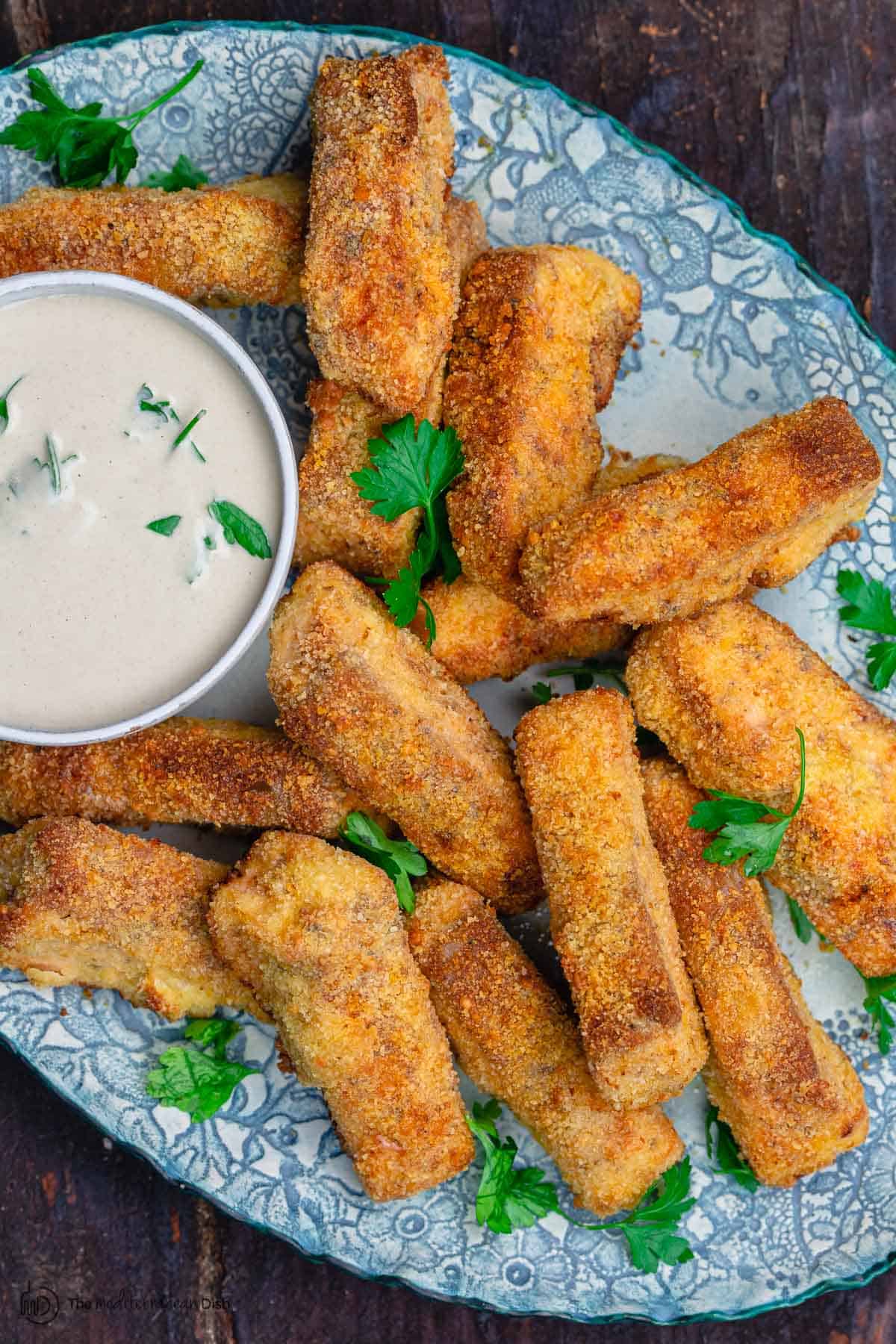 Salmon fish sticks on a platter with sauce