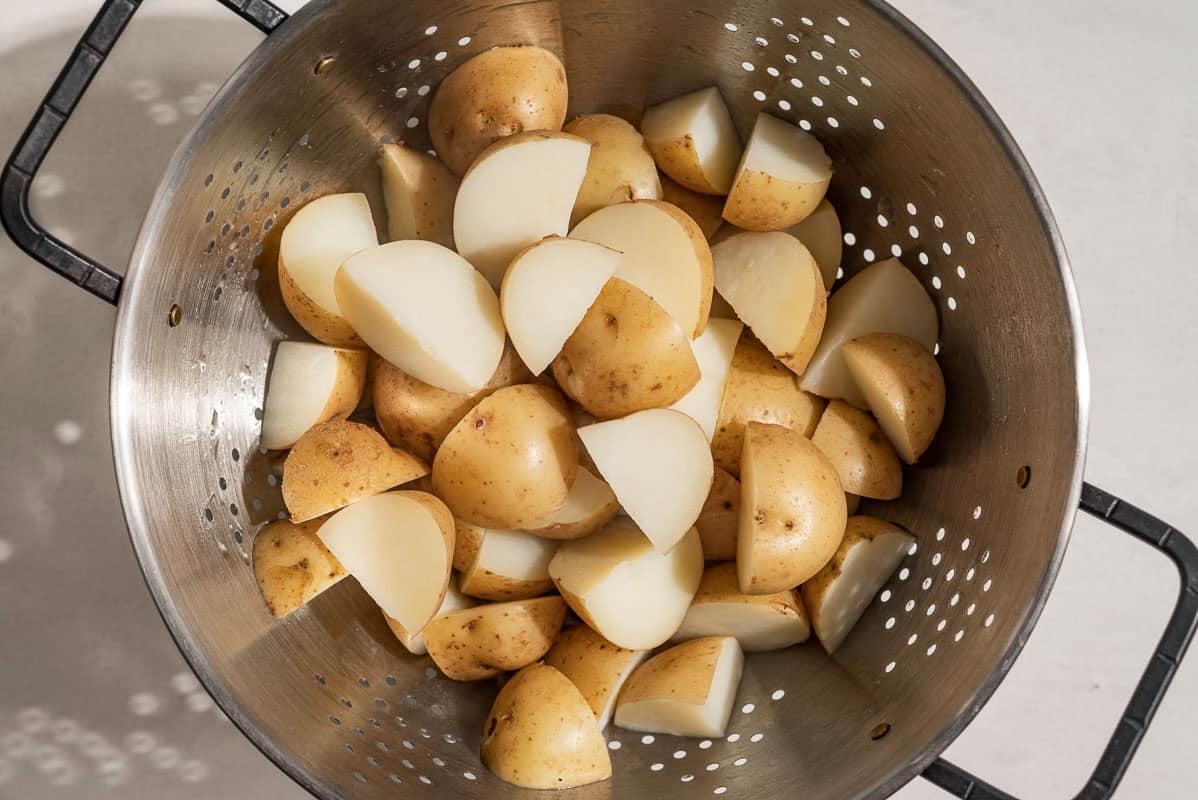 An overhead photo of quartered new potatoes in a colander.