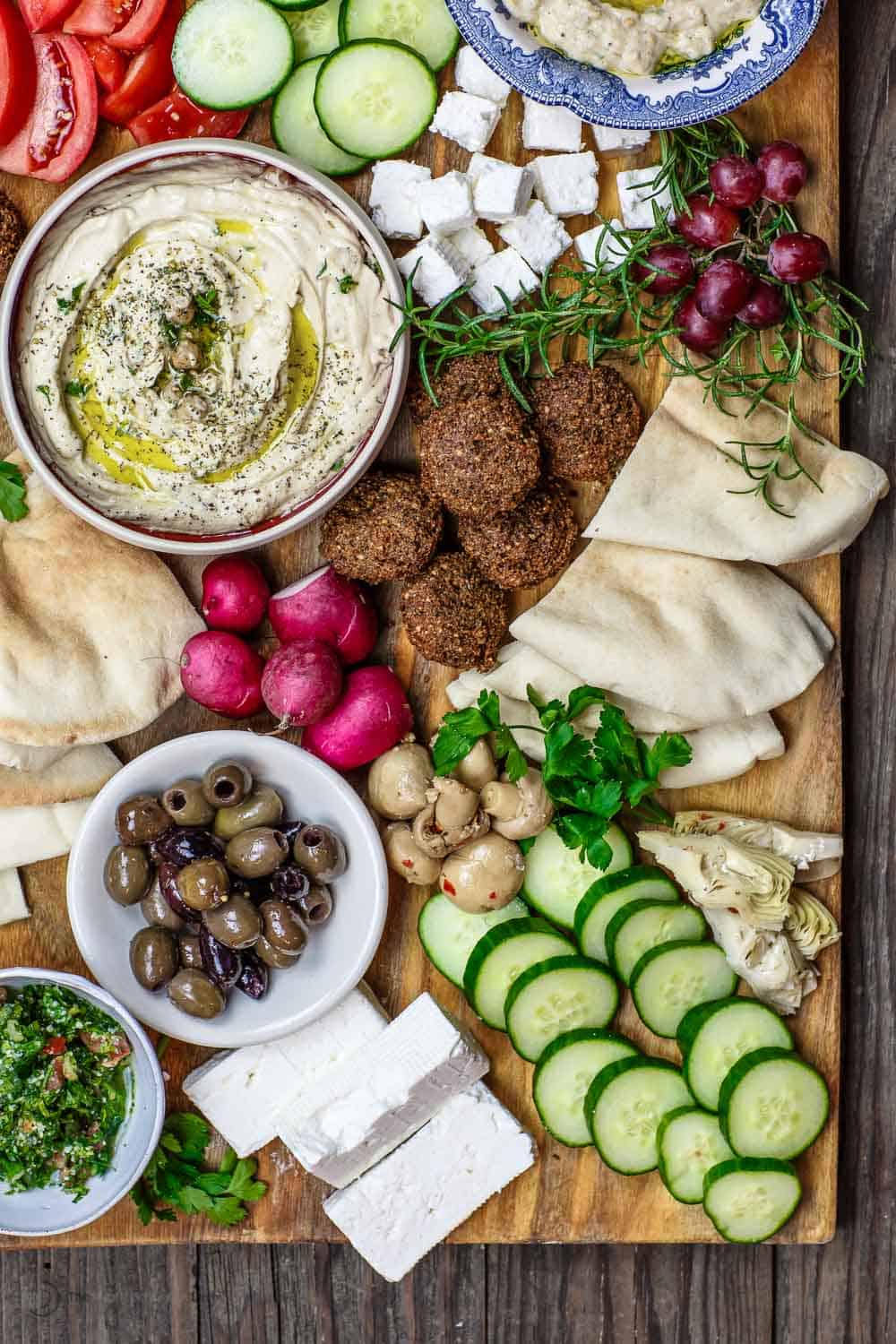 Mediterranean Diet Breakfast Board with falafel, hummus, black olives, feta cheese and veggies, served on a board.