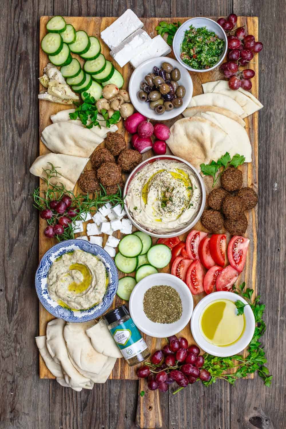 Mediterranean Diet Breakfast Board with falafel, hummus, black olives, feta cheese and veggies, served on a board.