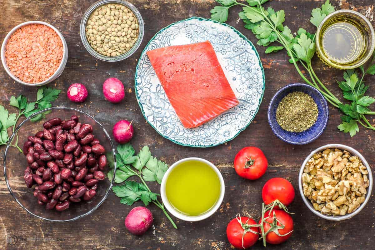 Table setting of Mediterranean ingredients including salmon, legumes, and nuts