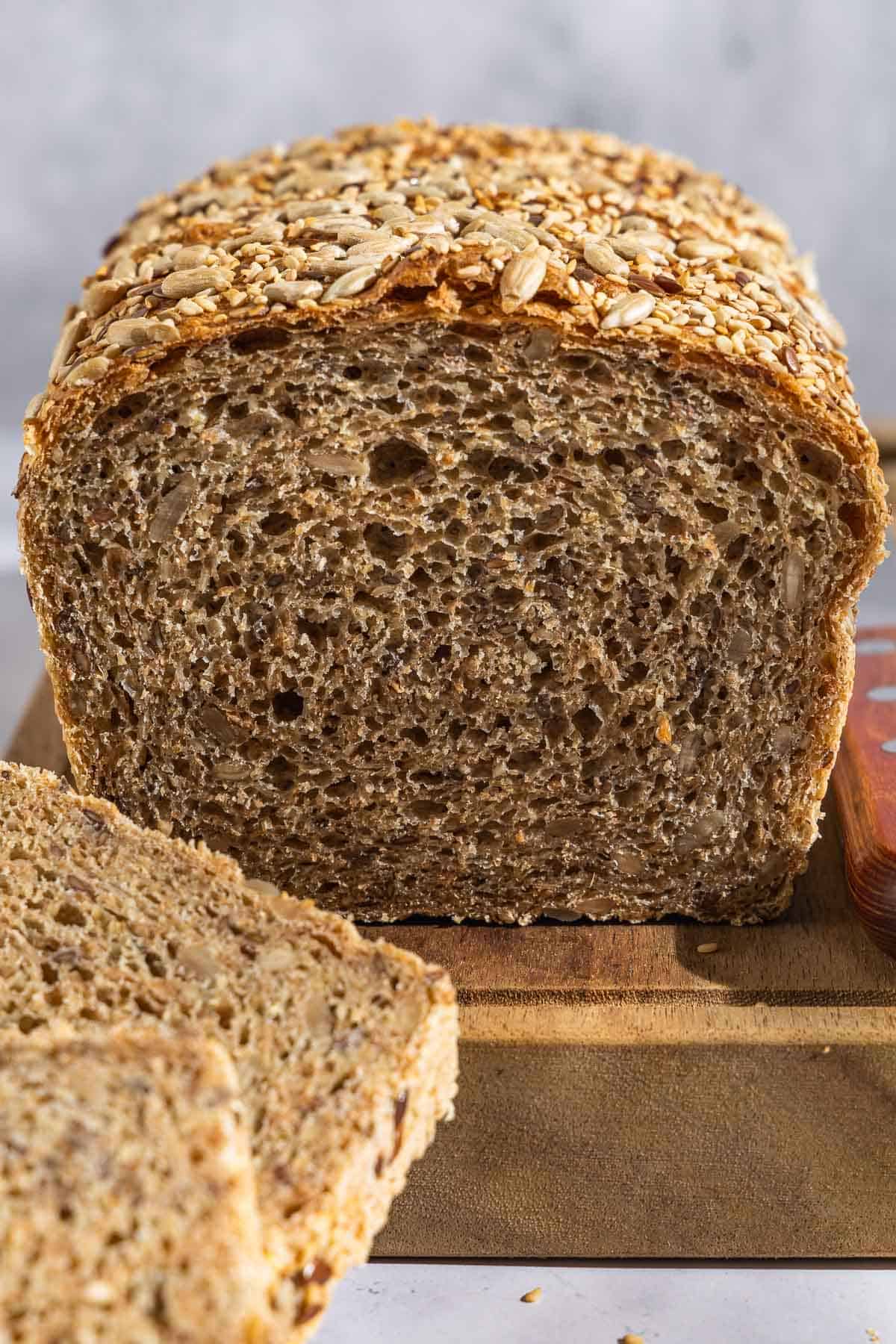 A close up photo of a partially sliced whole wheat bread loaf.