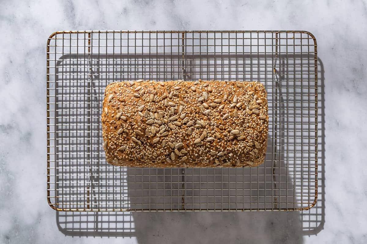 An overhead photo of a loaf of whole wheat bread on a wire rack.