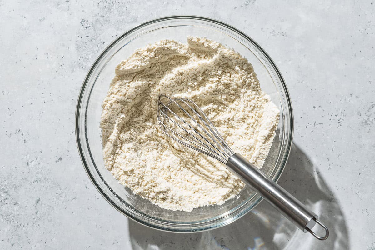 An overhead photo of the dry ingredients for the yogurt cake in a mixing bowl with a whisk.