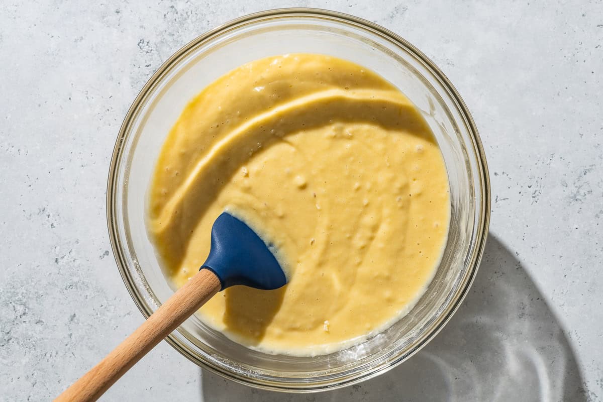 An overhead photo of the batter for the yogurt cake in a mixing bowl with a spatula.