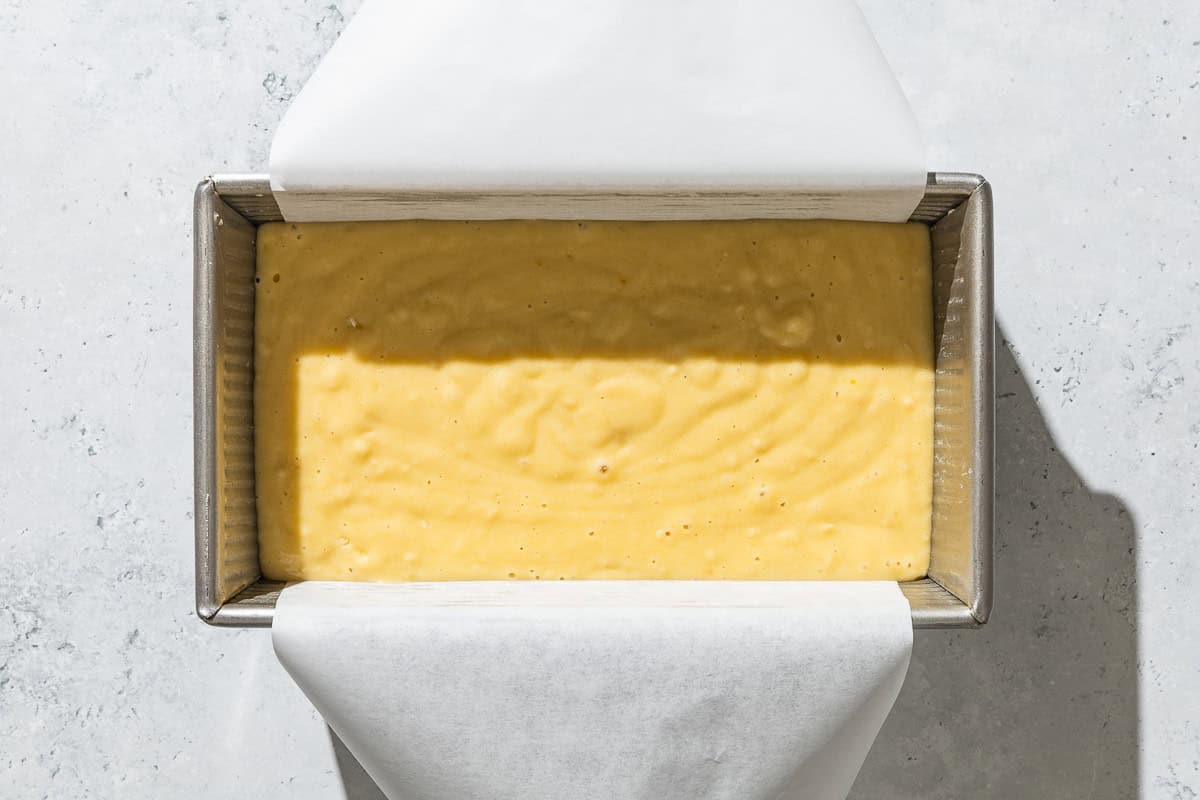 An overhead photo of the batter for the yogurt cake in a parchment lined loaf pan.