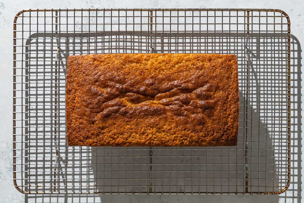 A baked yogurt cake cooling on a wire rack.