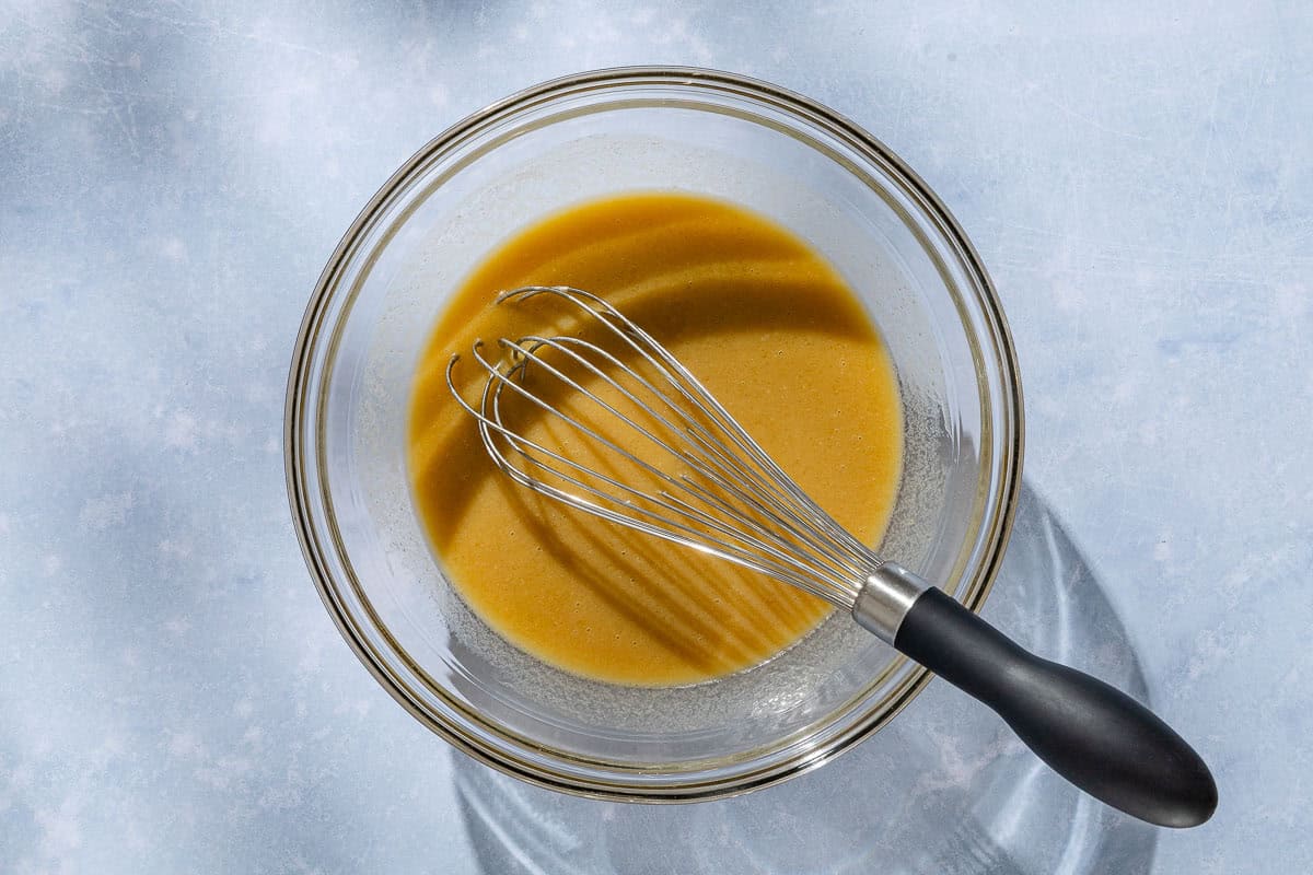 An overhead photo of the wet ingredients for the whole wheat fig bread in a bowl with a whisk.