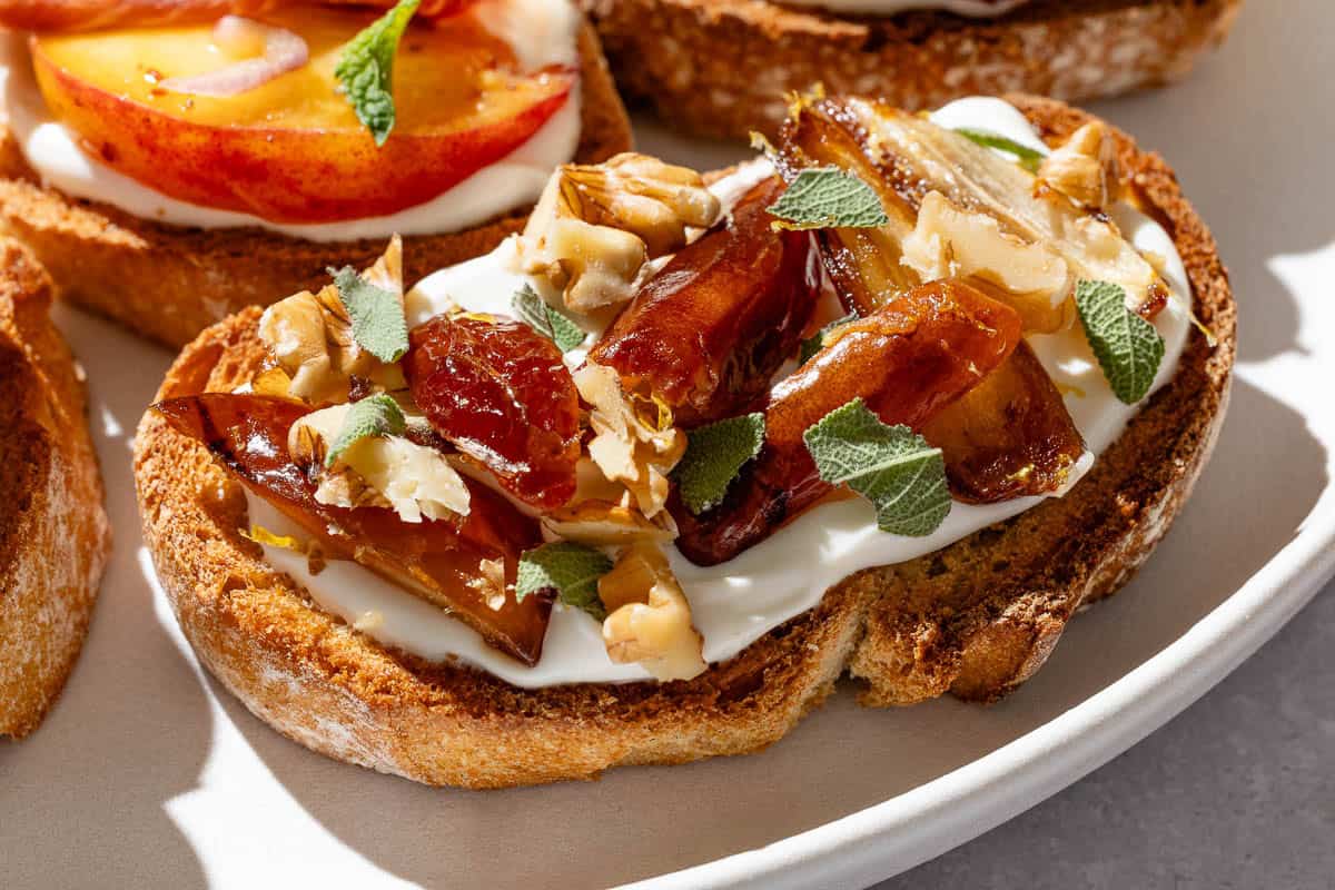 A close up of the warm date, walnut and sage ricotta toast on the serving plate.