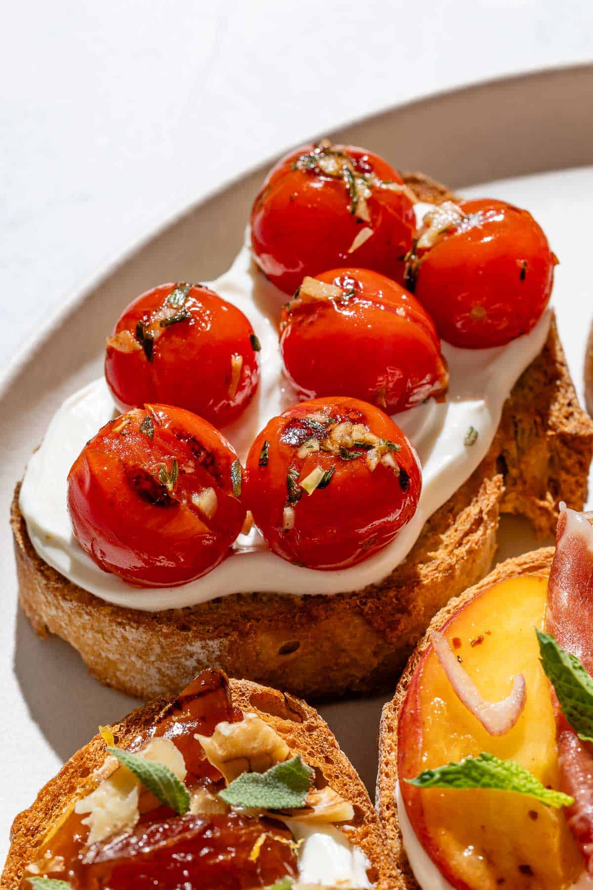 A close up of the blistered cherry tomato ricotta toast on the serving plate.