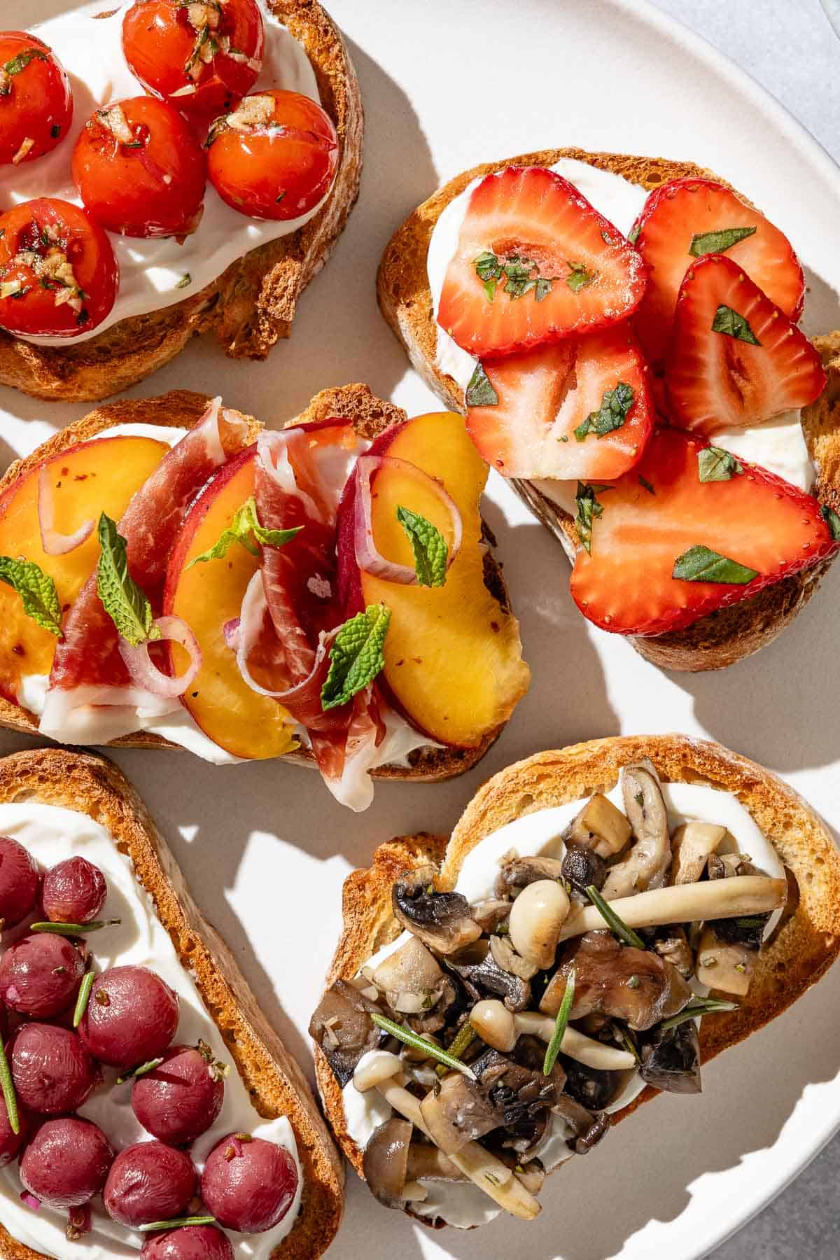 An overhead close up photo of an assortment of the ricotta toasts on a serving plate.