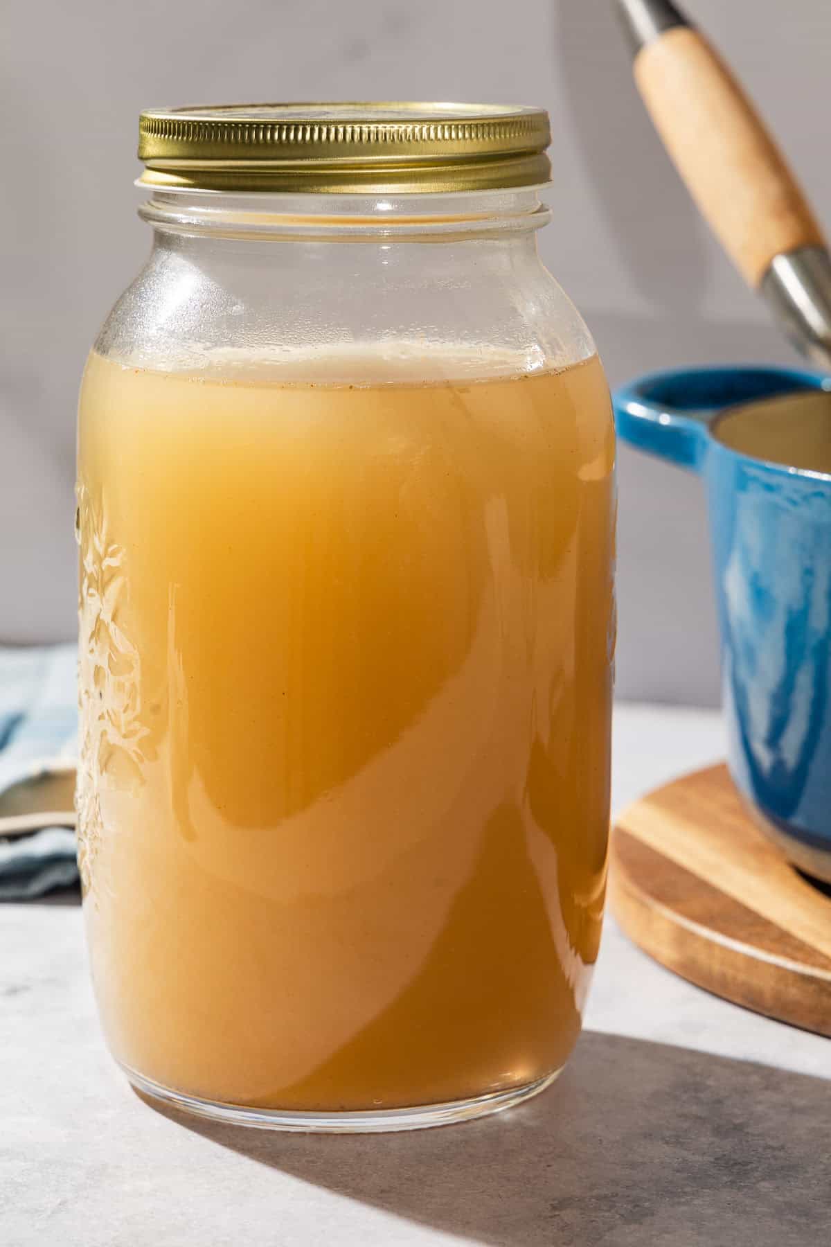 A close up of the seafood stock in a glass jar with a lid.