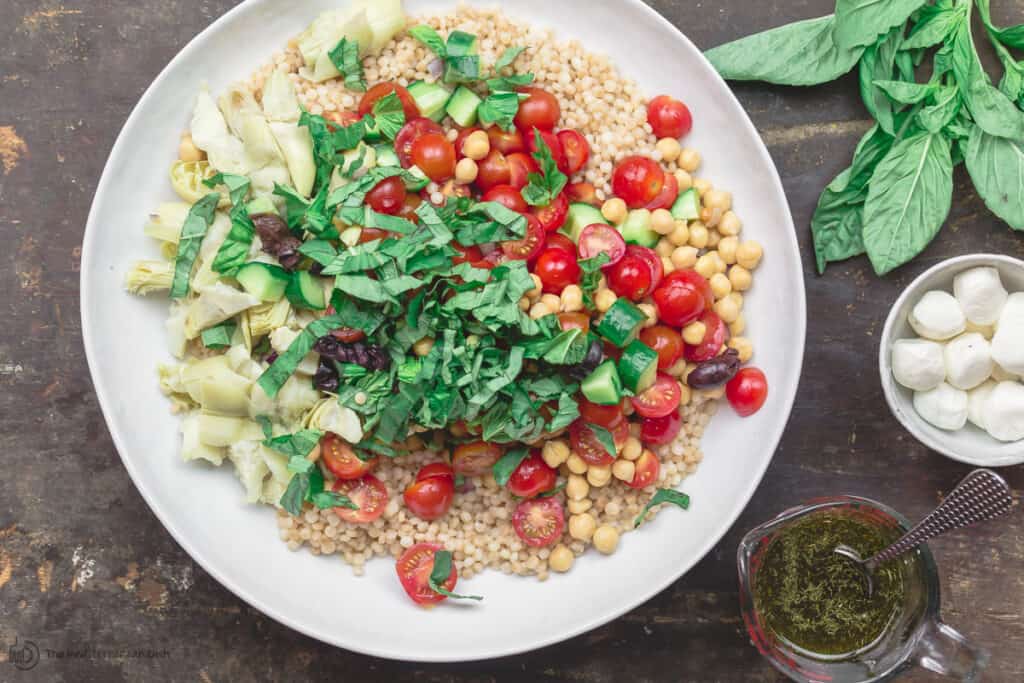 Ingredients for Mediterranean pearl couscous salad in a large mixing bowl