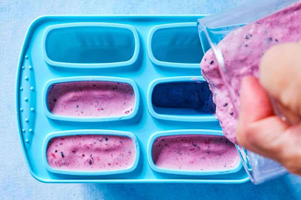 The homemade popsicle mixture being poured into popsicle molds.