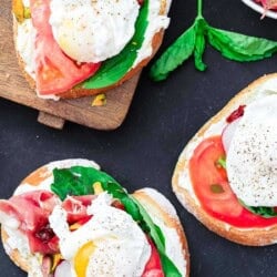 Three open faced sandwiches. One is on a cutting board and two are on the counter.