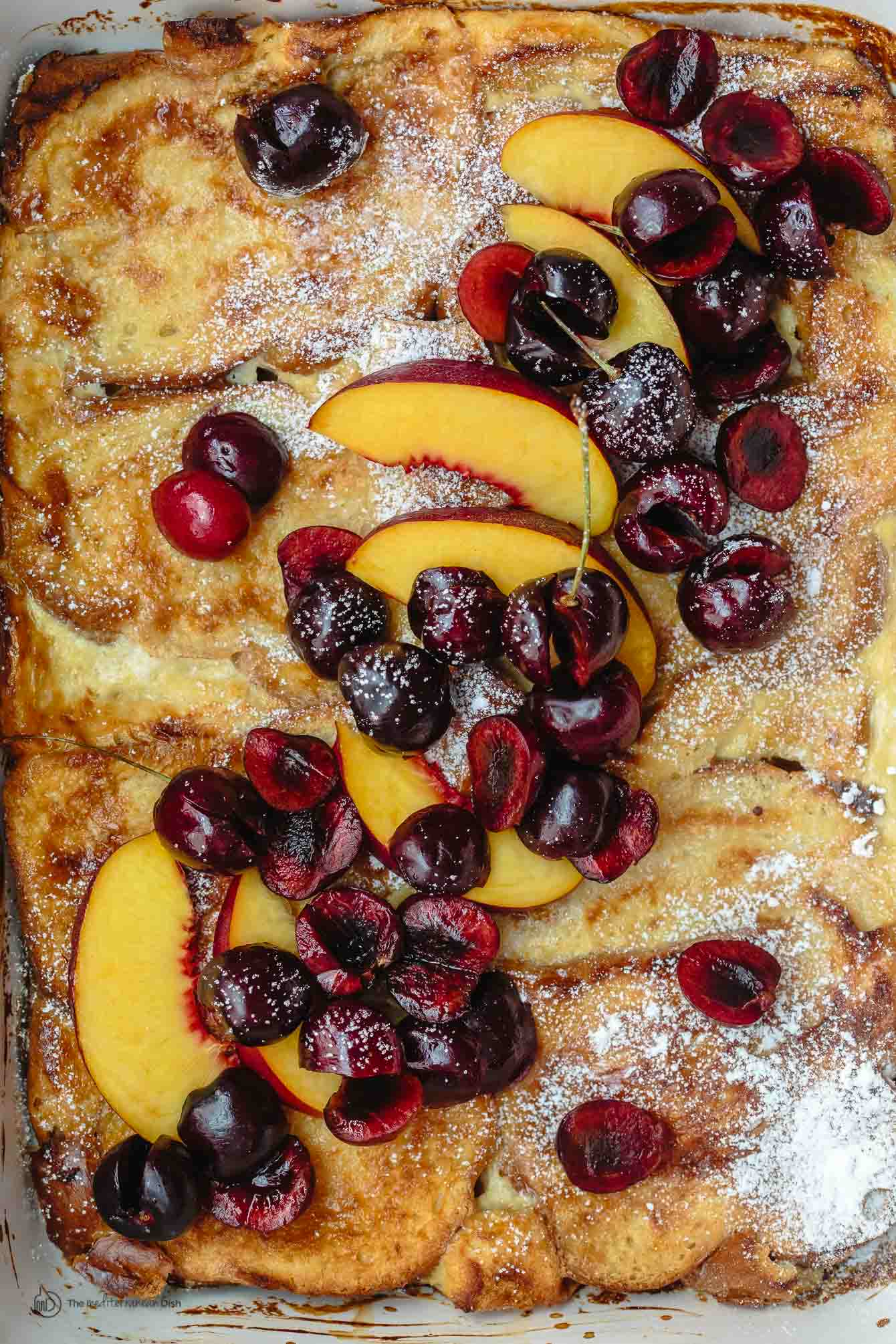 Overnight Baked French Toast Recipe with Challah | The Mediterranean Dish. Stupid easy and healtiher overnight french toast! Challah french toast with a reduced-fat yogurt custard, topped with fresh fruit and honey simple syrup. Prep it overnight and come morning, simply slip into the oven and enjoy your coffee!