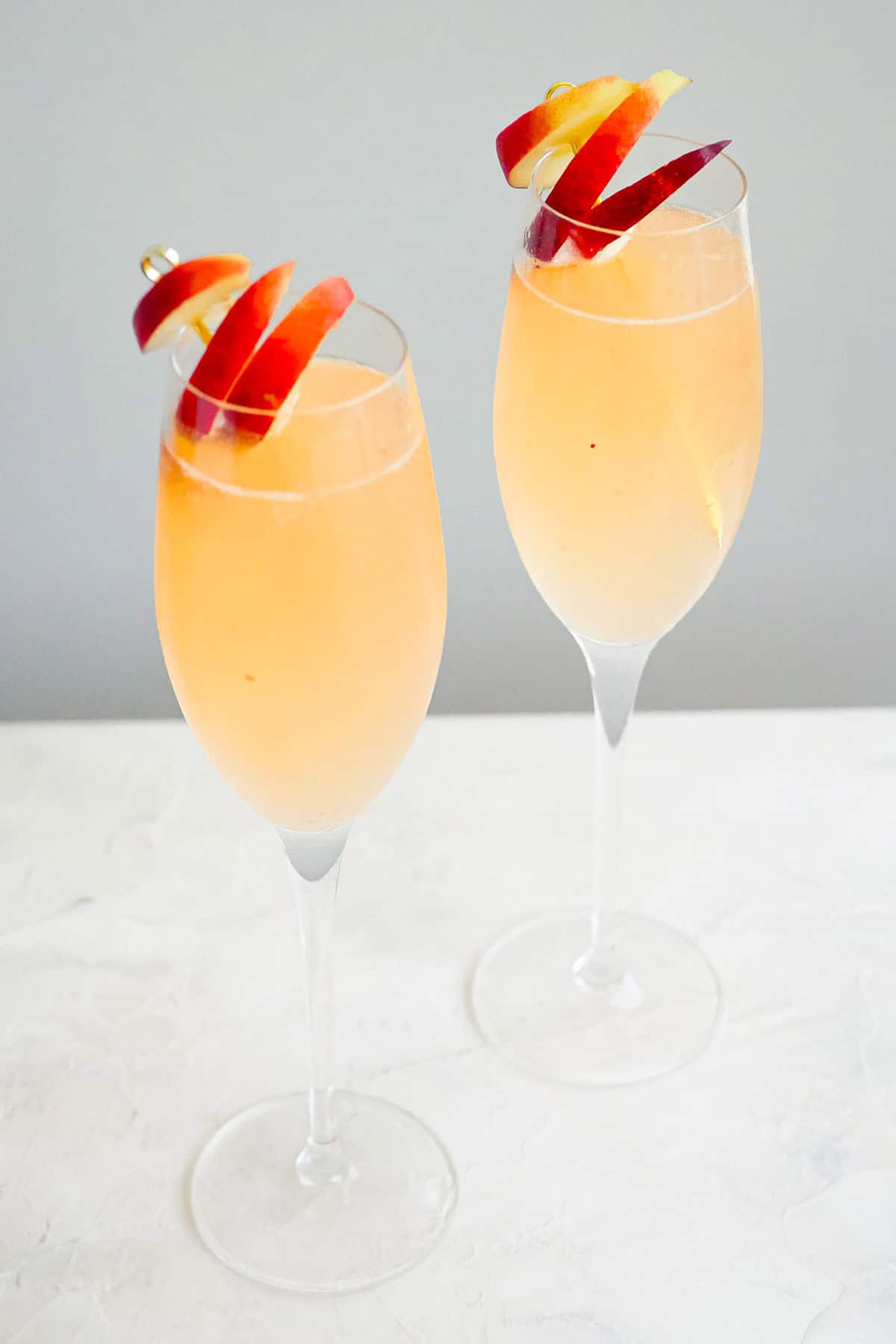 A close up of 2 peach bellinis garnished with peach slices.