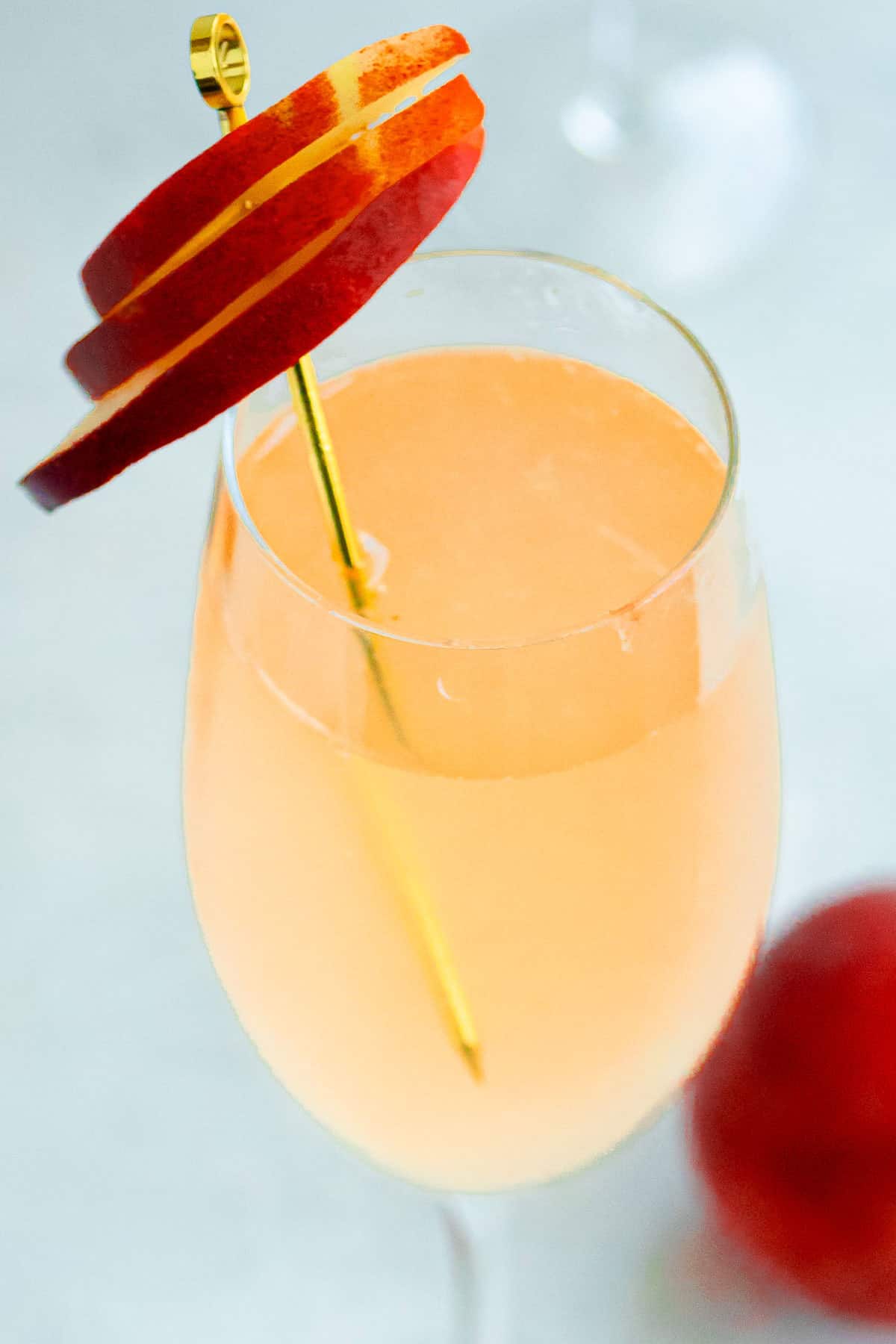 A close up of a peach bellini garnished with peach slices.