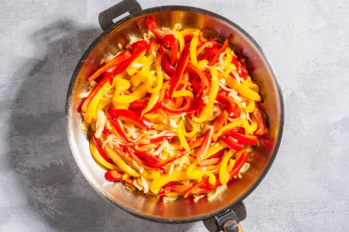 Vegetables for the peperonata in a skillet before being sauteed.