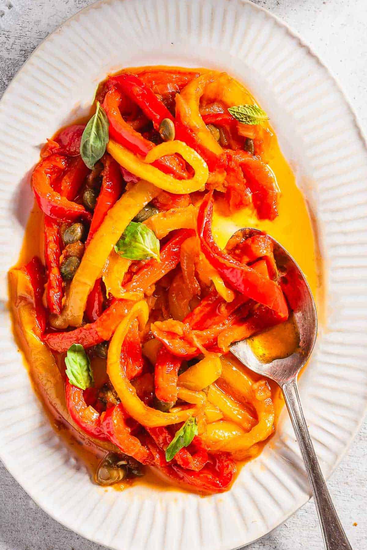 An overhead photo of peperonata on a serving platter with a spoon.