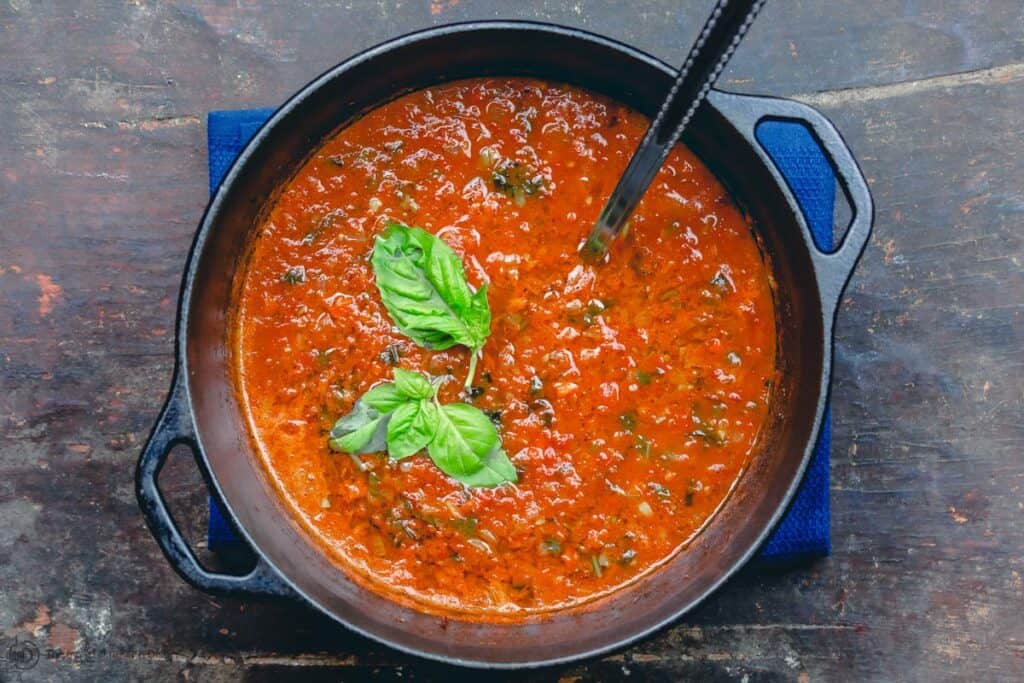 Roasted Tomato Basil Soup in a large pot with ladle. Garnished with basil