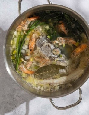 An overhead photo of all of the ingredients for the seafood stock simmering together in a large pot.