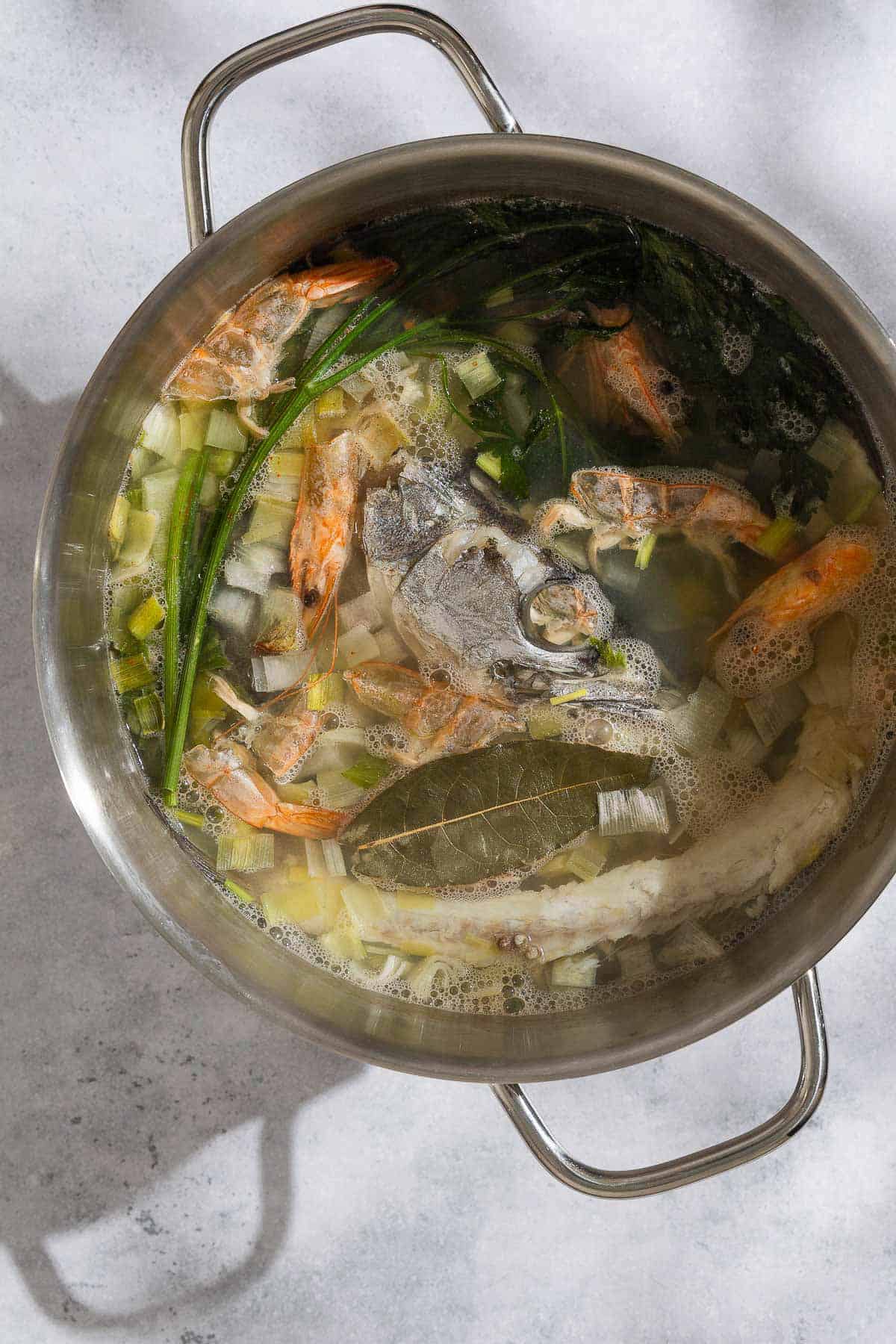 An overhead photo of all of the ingredients for the seafood stock simmering together in a large pot.