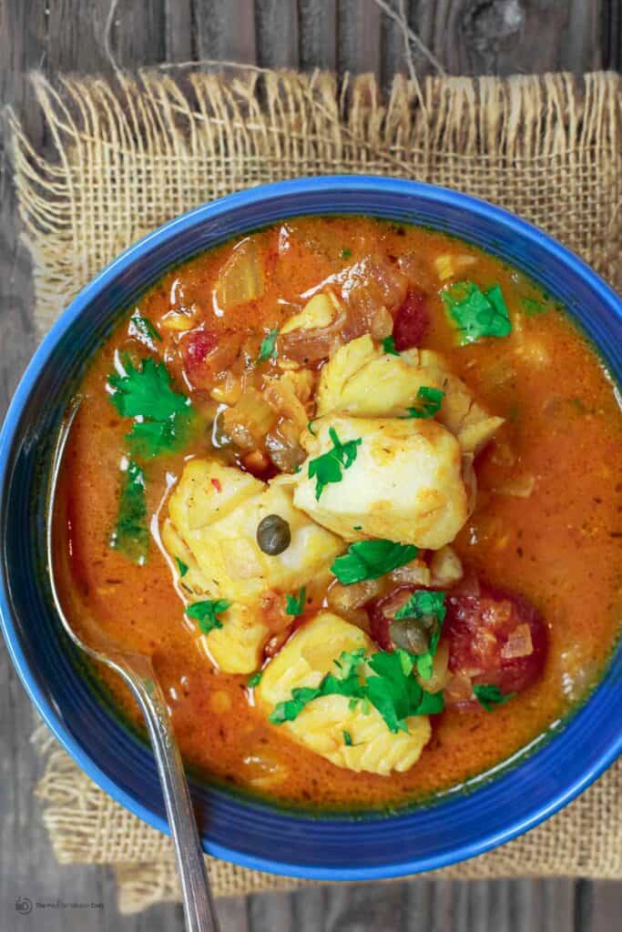 Sicilian Fish Stew Recipe | The Mediterranean Dish. Italian comfort in a bowl! My favorite! Fish fillet pieces cooked in a white wine and tomato broth with garlic, capers and more! Super easy and quick recipe. See it on TheMediterraneanDish.com