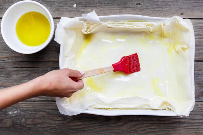 Phyllo sheets being brushed with olive oil