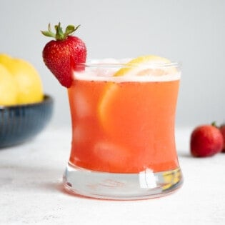 a glass of strawberry lemonade garnished with a strawberry and a lemon slice.