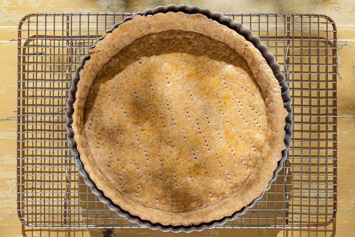 An overhead photo of the baked crust for the tomato tart cooling on a wire rack.