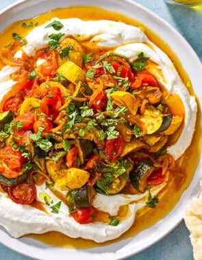 An overhead photo of borani kadoo on a serving plate. Next to this is a plate of pita pieces and a small bowl of chopped herbs.