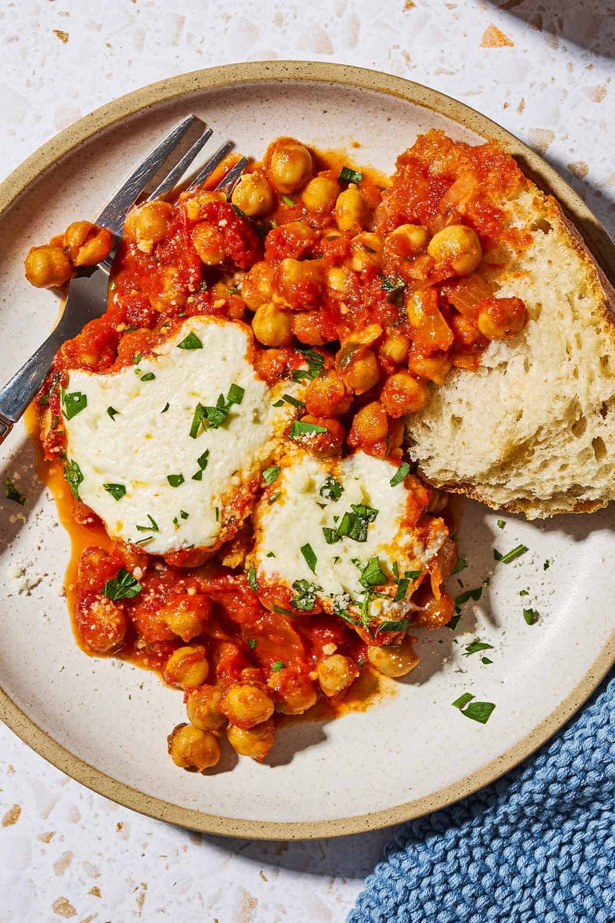 An overhead photo of a serving of chickpeas in tomato sauce on a plate with a fork.