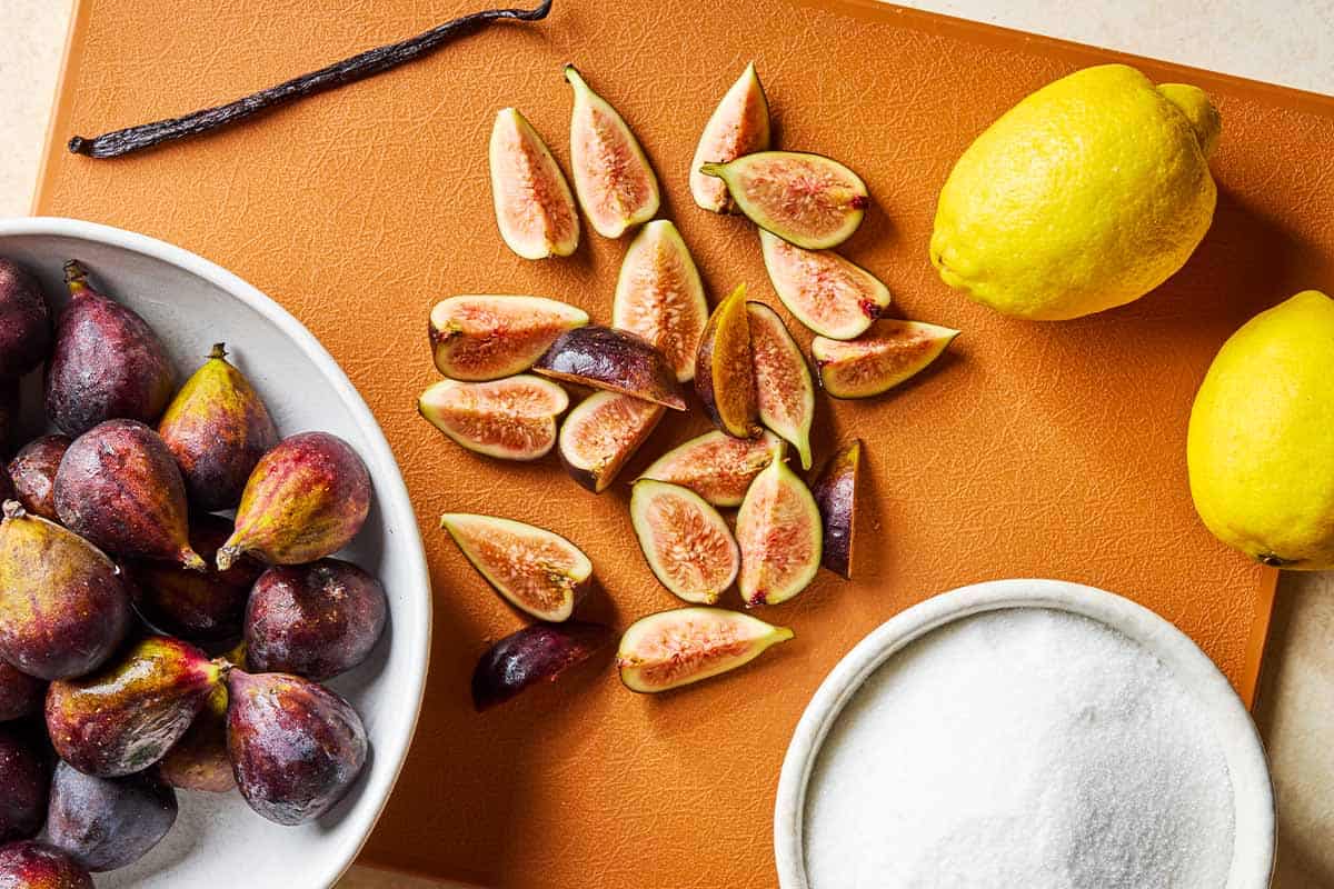 Ingredients for fig jam including whole vanilla bean, fresh figs, granulated sugar, and 2 lemons.